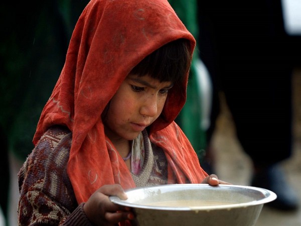 afghan refugee carries food at distribution center.