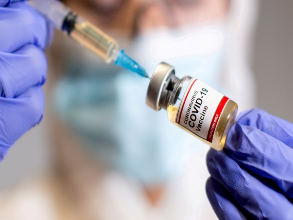 gfile photo: a woman holds a medical syringe and a small bottle labeled "coronavirus covid 19 vaccine