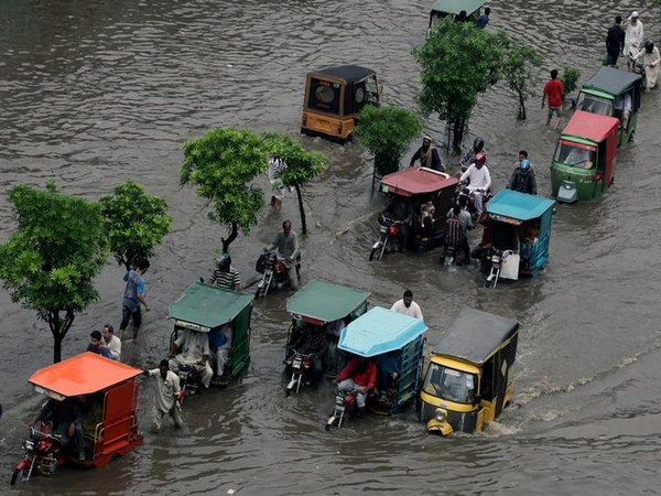 commuters on rickshaw and motorbikes pass through floodwaters after rain in lahore